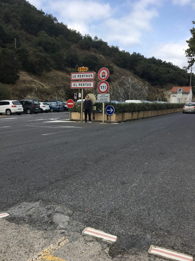 Town signs with pavement and cars showing the border between France and Spain